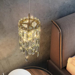 Gold tiered crystal pendant light hanging next to a bed