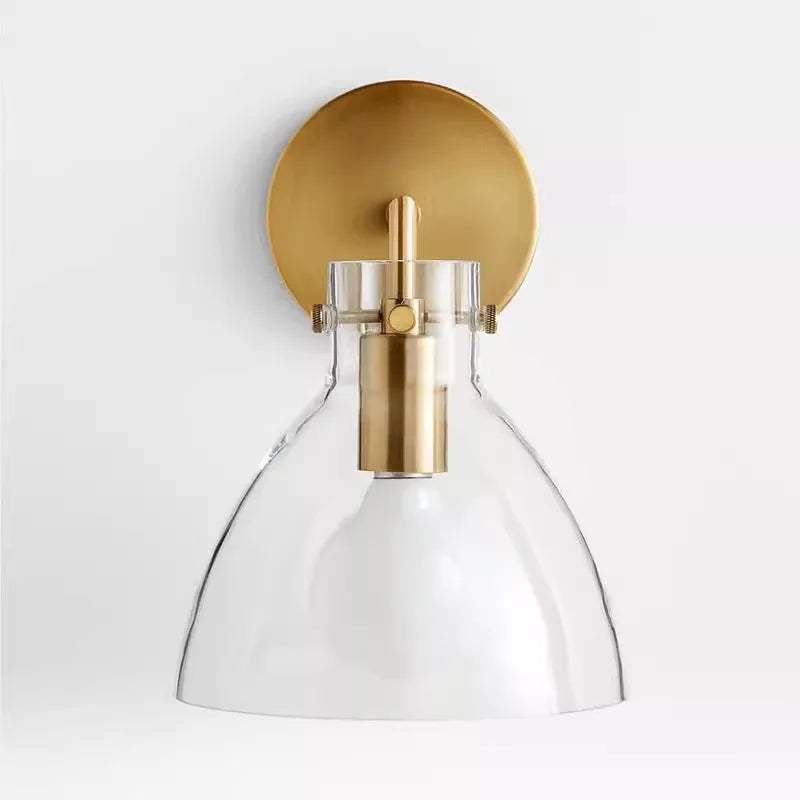 Close-up of the gold finish hardware and clear glass shade on a wall sconce.