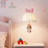 Pink bow fabric pendant light with a dangling doll, illuminating a child's bedroom.