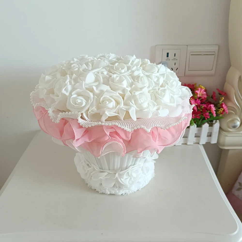 Decorative flower arrangement with white roses and pink accents on a white surface.