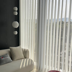 Modern interior with a sofa, decorative pillows, and a large window with vertical blinds.