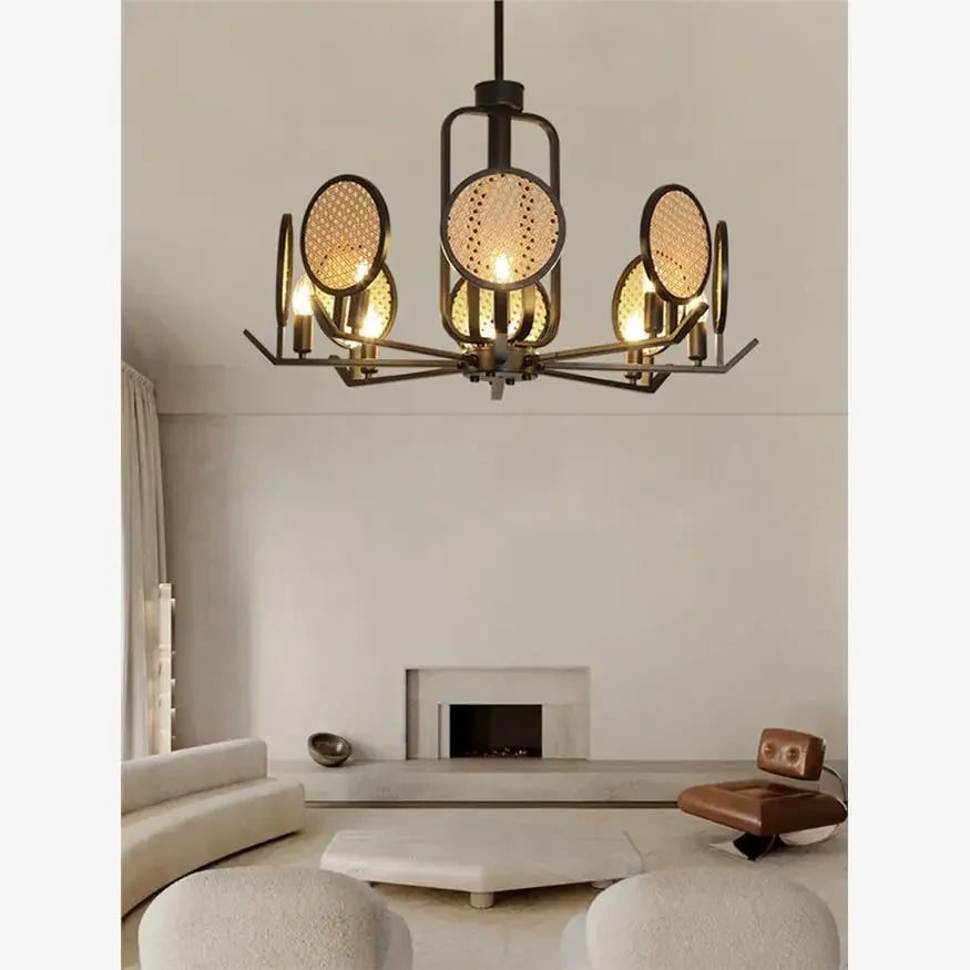 Chandelier with black metal frame and woven rattan discs in a living room setting with a fireplace.