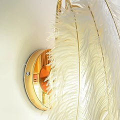 Decorative wall light fixture with feather-like design and gold frame.