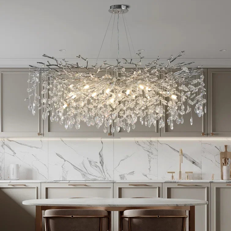 Chandelier hanging above a kitchen counter with marble backsplash and cabinets.