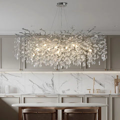 Chandelier hanging above a kitchen counter with marble backsplash and cabinets.