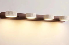 Modern wall-mounted light fixture with four cylindrical lights on a plain background