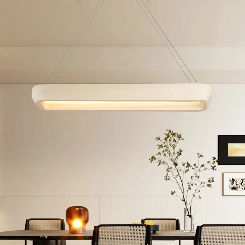 Modern pendant light fixture in a room with tables and decor