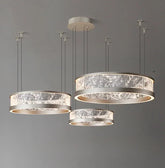 Collection of three ring-shaped pendant lights with textured glass diffusers and silver-toned metal frames, suspended from a grey ceiling.