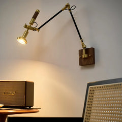 Brass and black adjustable swing arm wall sconce mounted on a white wall, with a walnut wood base.