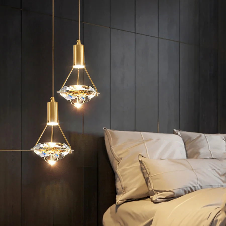 Gold pendant lights hanging above a bed with a dark paneled wall.