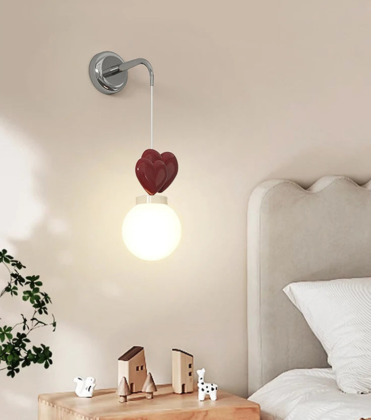 Heart-shaped wall lamp in a bedroom setting with a bed and nightstand.