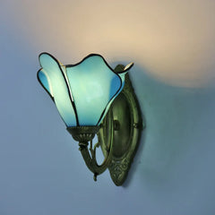 Wall-mounted light fixture with stained glass shade on a blue wall