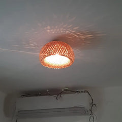 Woven bamboo dome ceiling light mounted on a white ceiling, with a patterned light projection.
