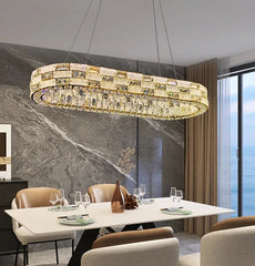 Modern dining room with a large oval chandelier, marble wall, and large window.