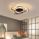 Black spiral swirl flush mount LED ceiling light fixture mounted on a white ceiling in a bedroom setting.