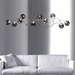 Chrome spiral wave pendant light with multiple smoky gray glass globes hanging above a white sofa.