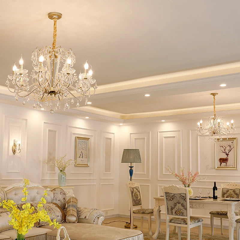 Living room with two gold chandeliers, one large in the foreground, one smaller in the background.