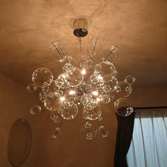 A large glass ball starburst chandelier with multiple clear glass spheres and integrated LED lights, suspended from a chrome ceiling mount.