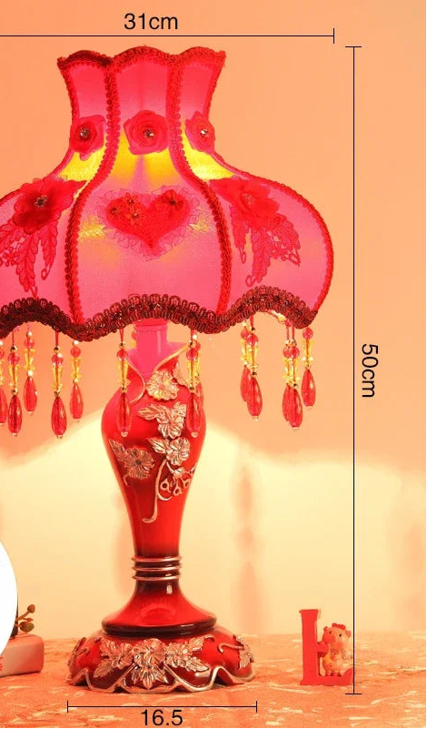 Decorative red table lamp with floral patterns and measurements on a warm background