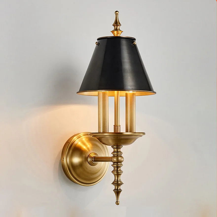 Wall-mounted lamp with black shade and gold fixture on a light gray background
