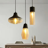Three pendant lights with ribbed glass shades and dark tops hanging over a dining table.