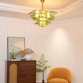 Green glass chandelier with layered leaf design and polished copper accents hanging from a white ceiling.