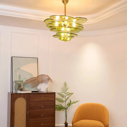 Green glass chandelier with layered leaf design and polished copper accents hanging from a white ceiling.
