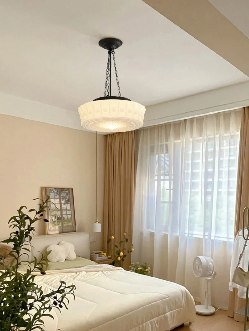 Modern bedroom with a ceiling light fixture, bed, and window with curtains.