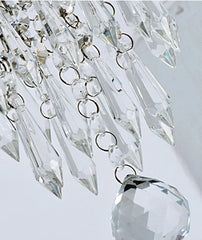 Close-up of a crystal chandelier with clear glass prisms on a light gray background