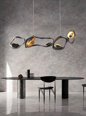 Modern dining table with chairs and a stylish pendant light fixture against a gray wall.