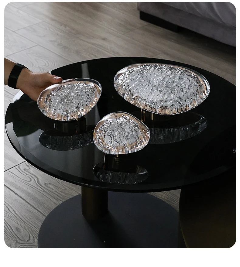 Black round table with three decorative glass bowls on a wooden floor.