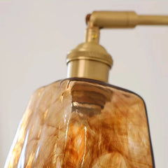 Gold-toned soap dispenser with a textured glass bottle on a plain background