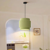 Green tiered resin pendant light hanging in a dining room