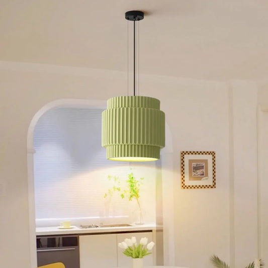 Green tiered resin pendant light hanging in a dining room