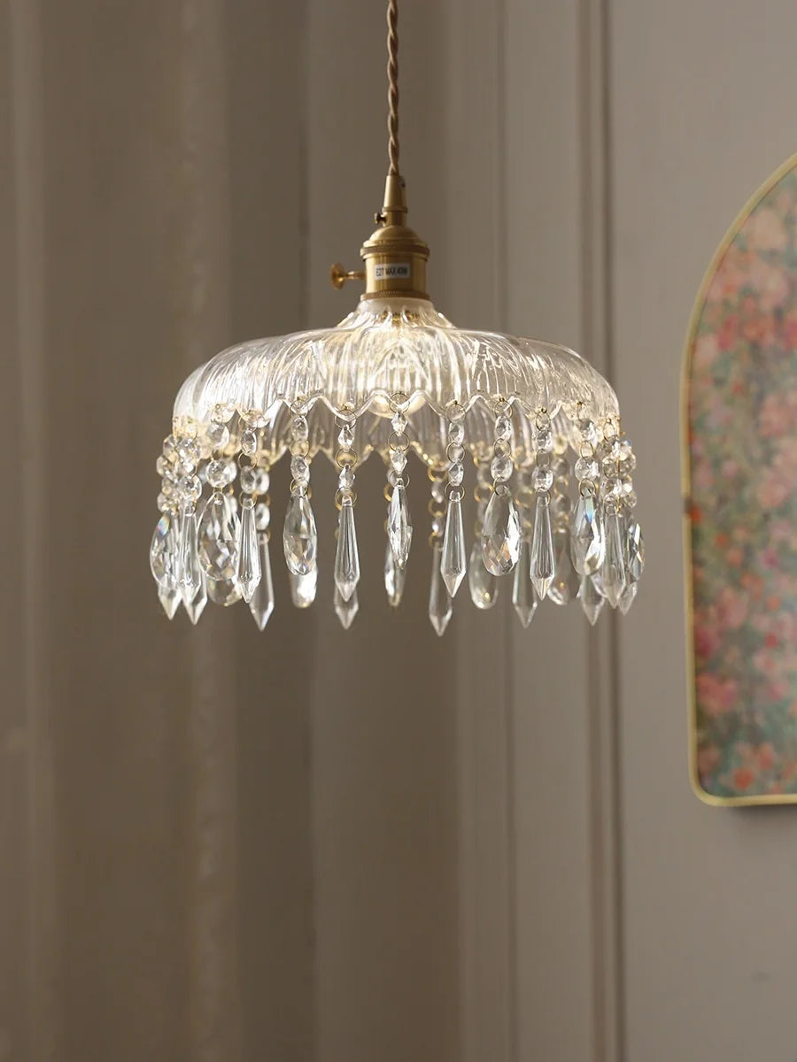 Crystal chandelier hanging against a neutral wall with a floral mirror in the background