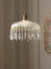 Crystal chandelier hanging against a neutral wall with a floral mirror in the background