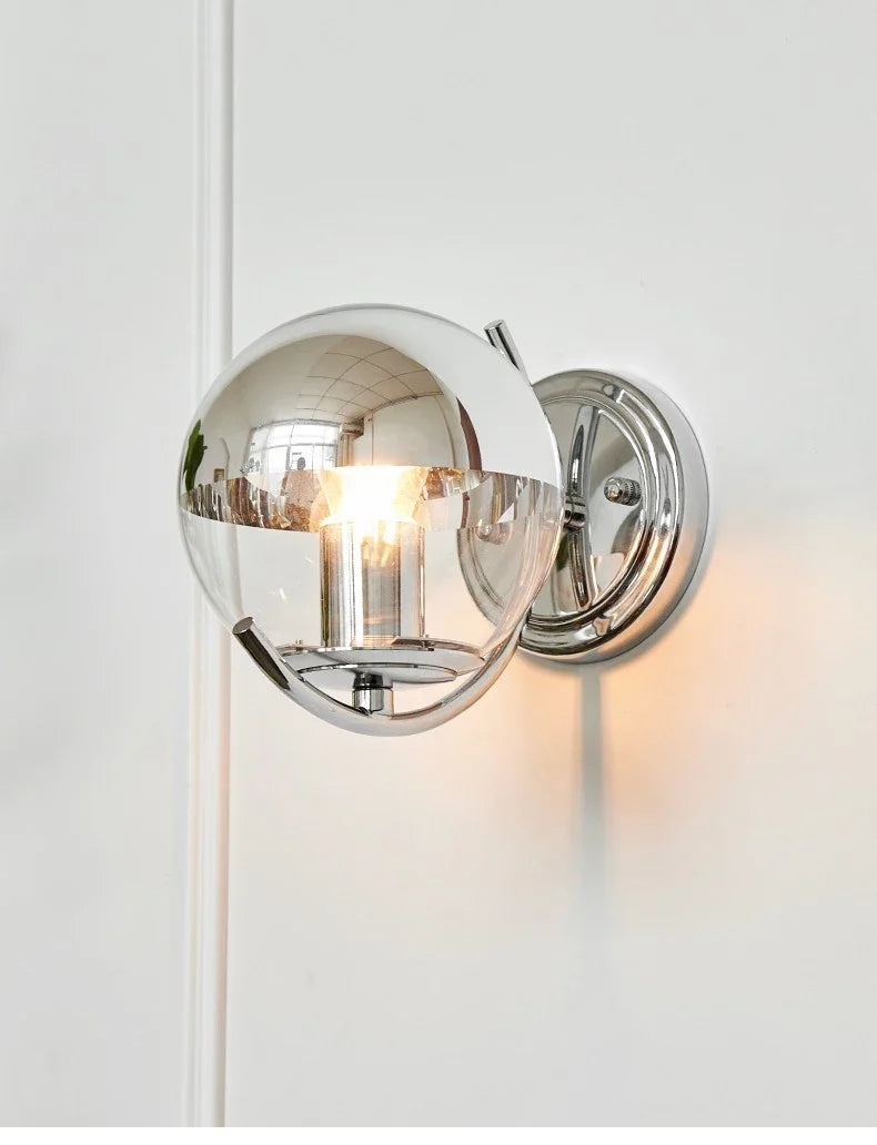 Chrome wall sconce with a light on a white wall