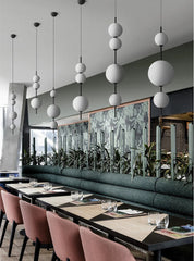 Modern restaurant interior with long dining table, pink chairs, and decorative wall art.