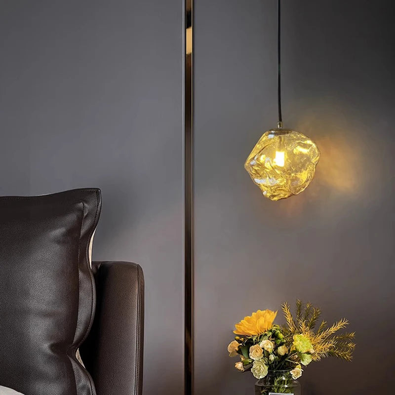 Modern pendant light fixture hanging above a vase with flowers on a dark gray wall.