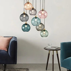 Close-up of a single colorful textured glass globe pendant light with a polished gold fitting