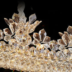 Detail shot of the crystal and floral elements on the polished chrome chandelier, with visible light refractions.