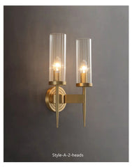 Gold wall sconce with two clear glass shades on a gray background