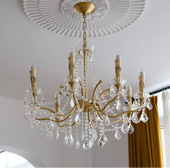 Gold chandelier with crystal accents hanging from a decorative ceiling.