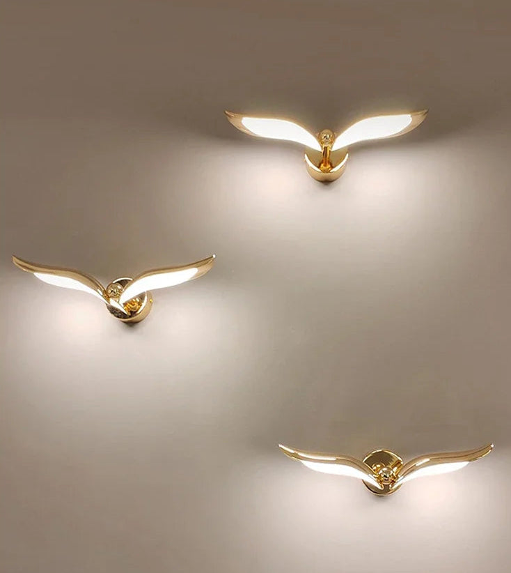 Three gold bird-shaped wall lights on a beige background