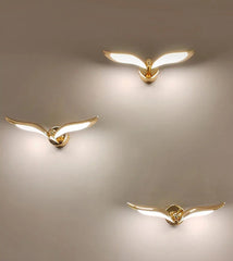 Three gold bird-shaped wall lights on a beige background