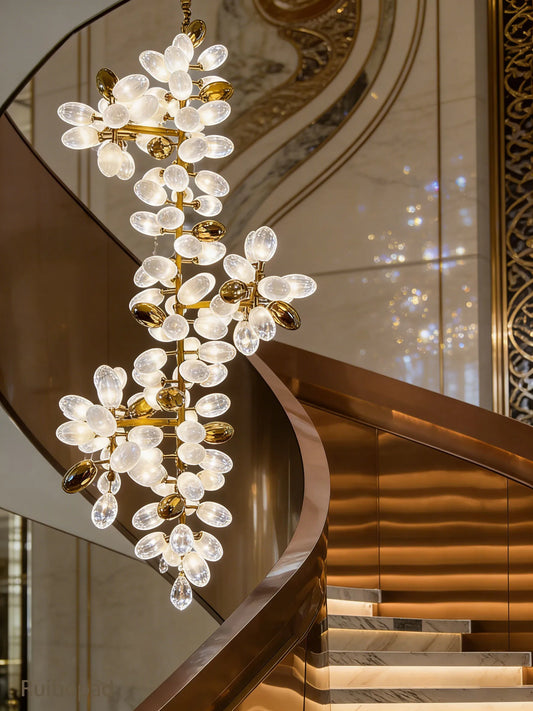 Close-up of a gold floral cluster chandelier with opal glass shades and a curved staircase.
