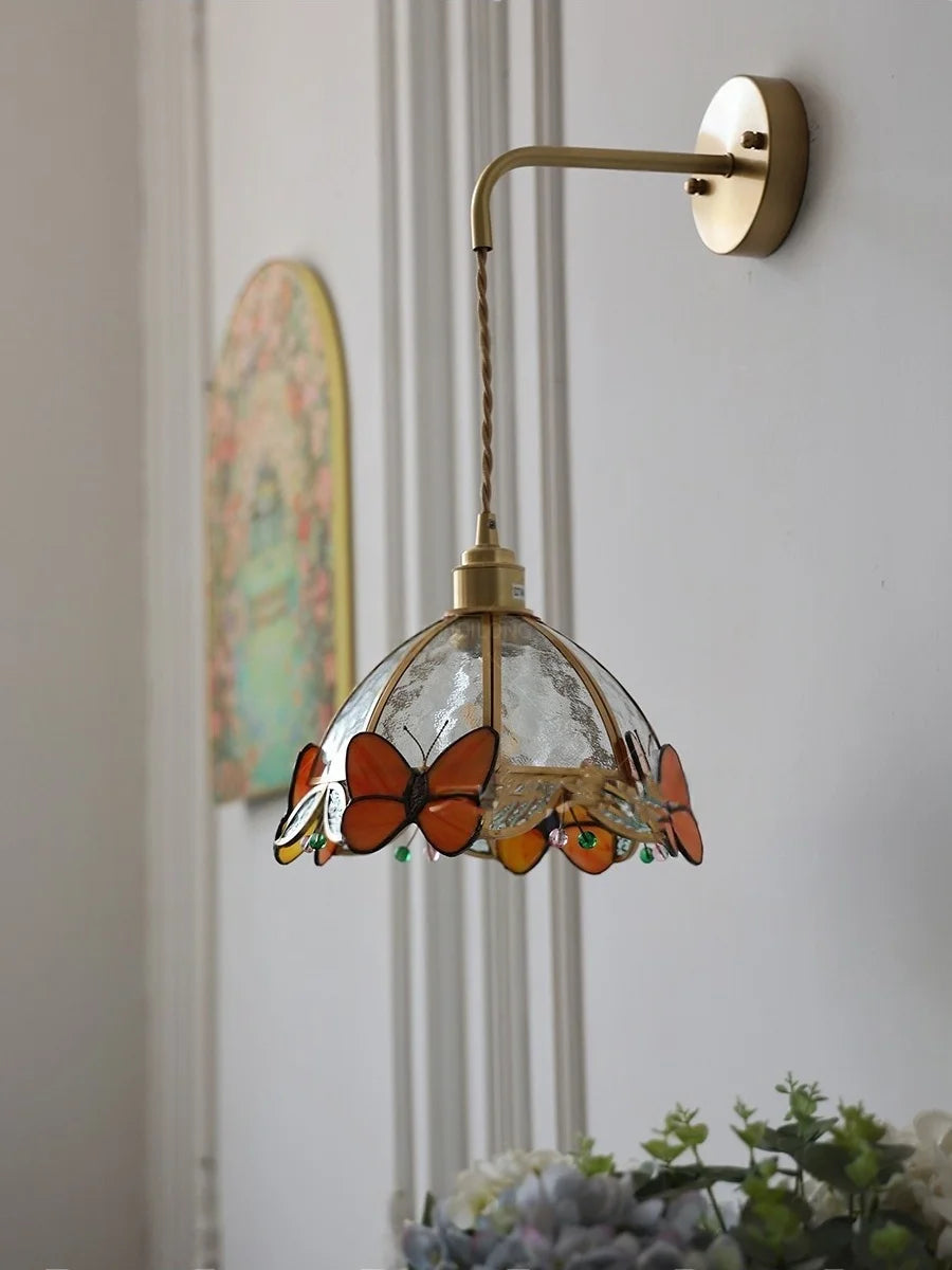 Wall-mounted light fixture with butterfly design on a neutral background