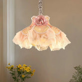 Close-up of a fabric pendant light with a pink rose accent and tiered, ruffled pink and yellow fabric shades.