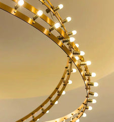 Gold circular light fixture with multiple bulbs on a neutral background