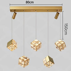 Gold pendant light fixture with crystal-like shades and measurements on a gray background